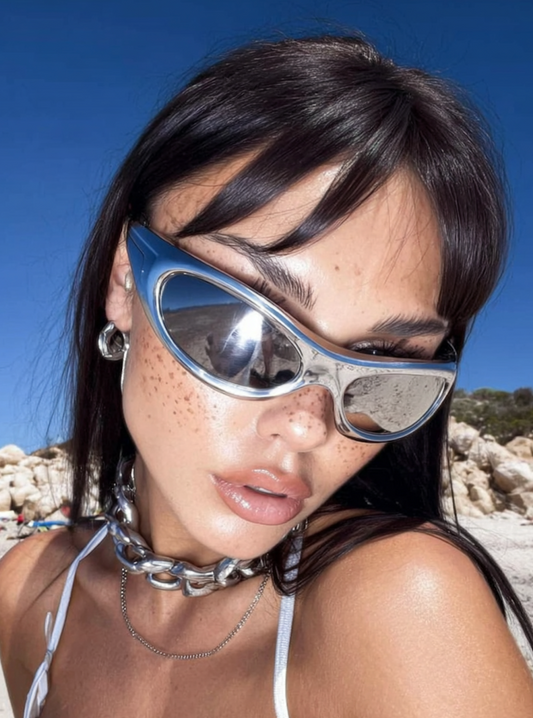 Woman on a beach with freckled skin and chrome wraparound sunglasses